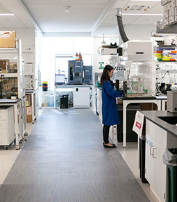 A woman in a blue lab coat performing an experiment in a lab