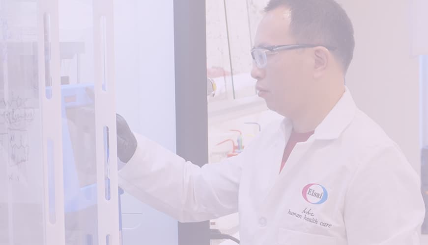 A male scientist wearing a lab coat and a pair of safety glasses, conducting laboratory research