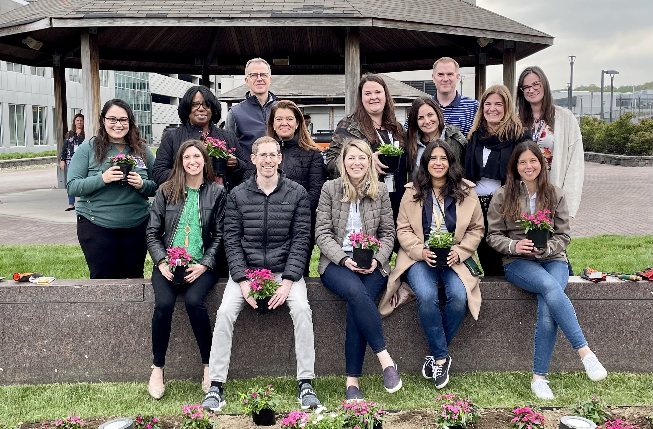 A group of Eisai employees gathered outside holding potted flowers