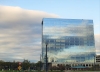A large corporate building with glass exterior and clouds in the skyline