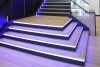 A set of lobby stairs with purple stair lighting and glass siding