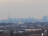 A city in the foreground with the New York City skyline in the background during sunrise