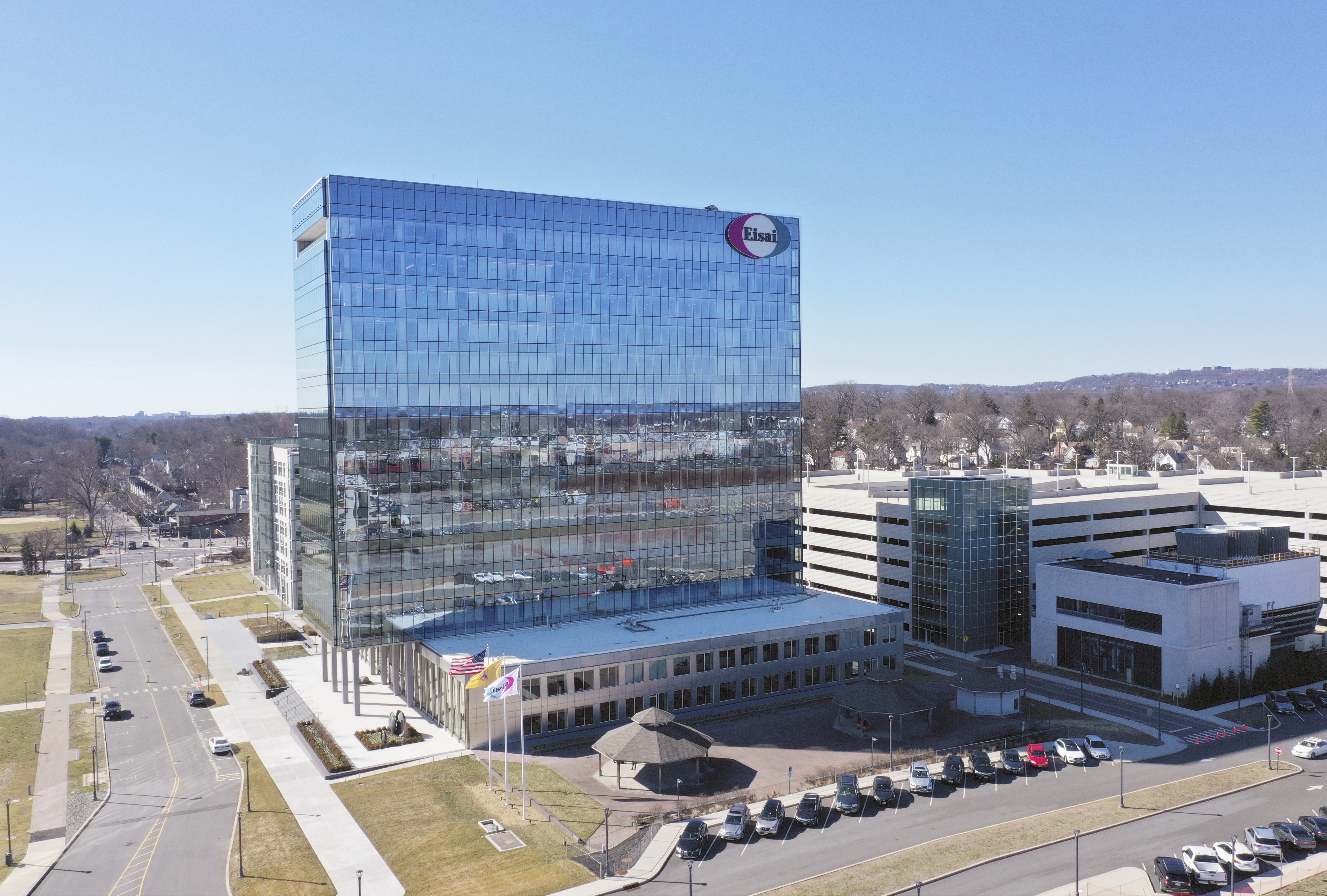 A street-view of a corporate Eisai building with glass exterior and clouds in the skyline